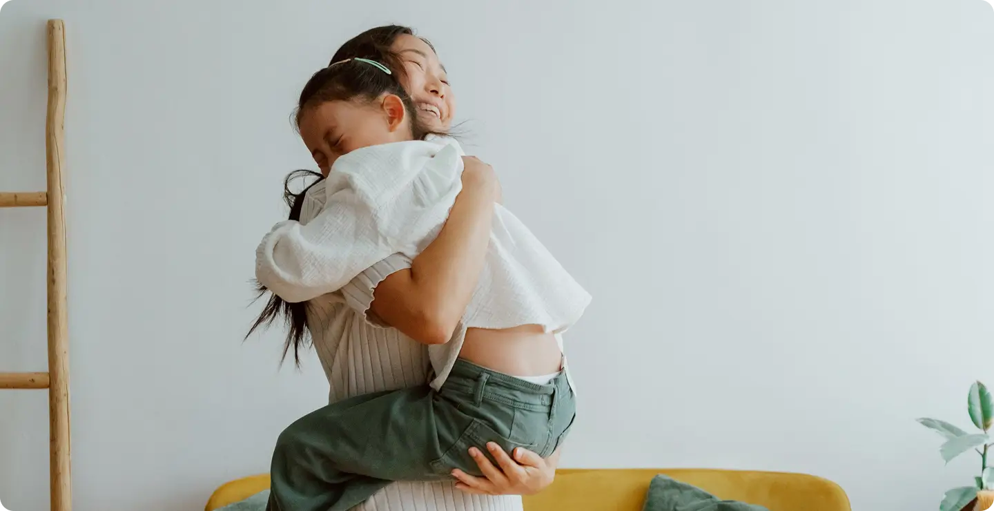 A parent holding a smiling child in a warm embrace